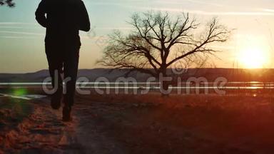 剪影人在日落时沿着道路<strong>奔跑</strong>，独自站在树上剪影。 在大自然中<strong>奔跑</strong>的运动青年